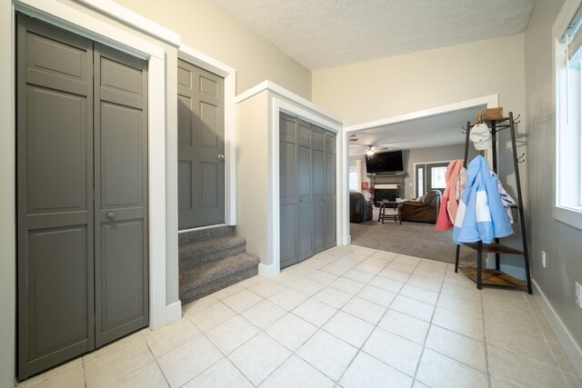 hall with a wealth of natural light, light tile patterned flooring, and a textured ceiling