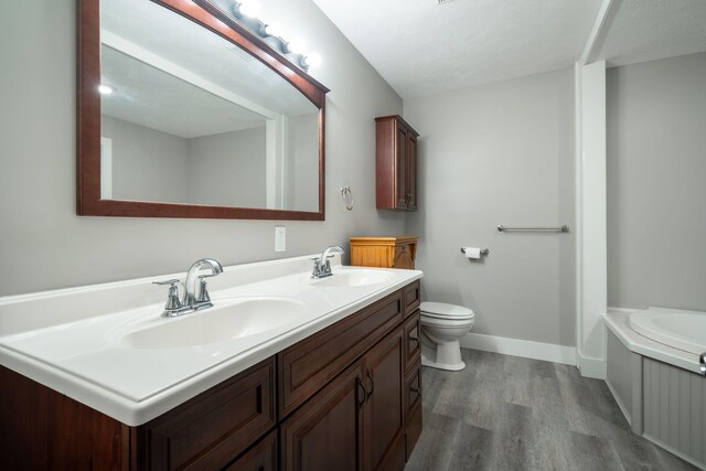 bathroom with a bathing tub, vanity, wood-type flooring, and toilet