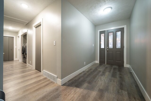 foyer with hardwood / wood-style flooring, independent washer and dryer, and a textured ceiling