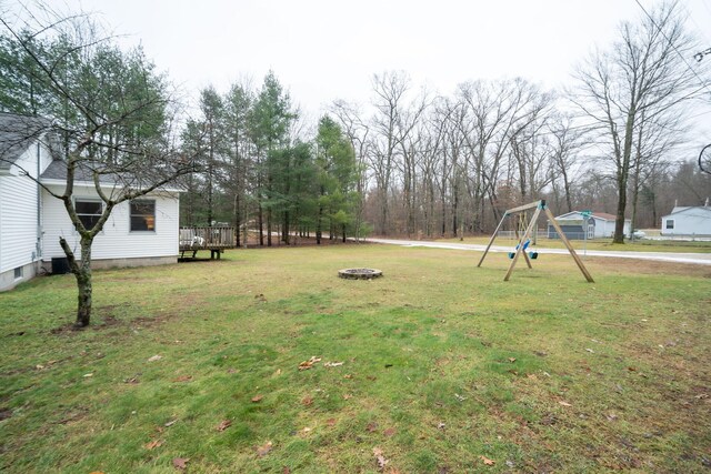 view of yard with a playground, a deck, and an outdoor fire pit