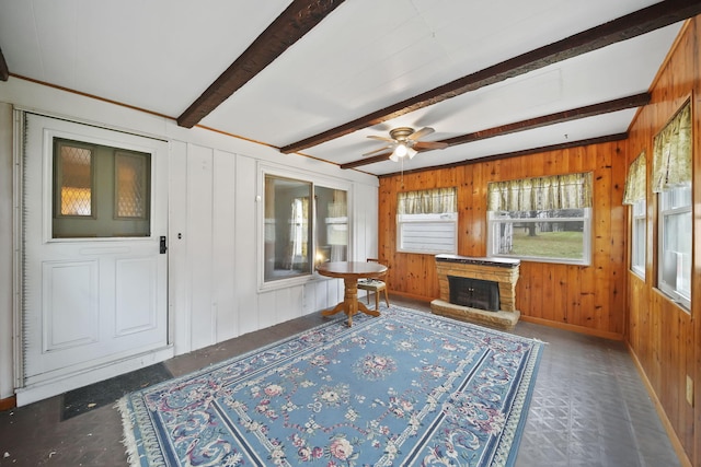 unfurnished sunroom with beam ceiling, a stone fireplace, and ceiling fan