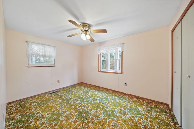 unfurnished bedroom with multiple windows, ceiling fan, a closet, and carpet floors