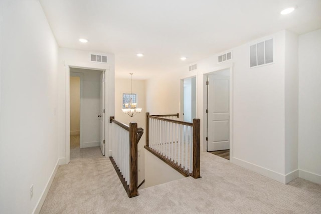 hall with a chandelier and light colored carpet