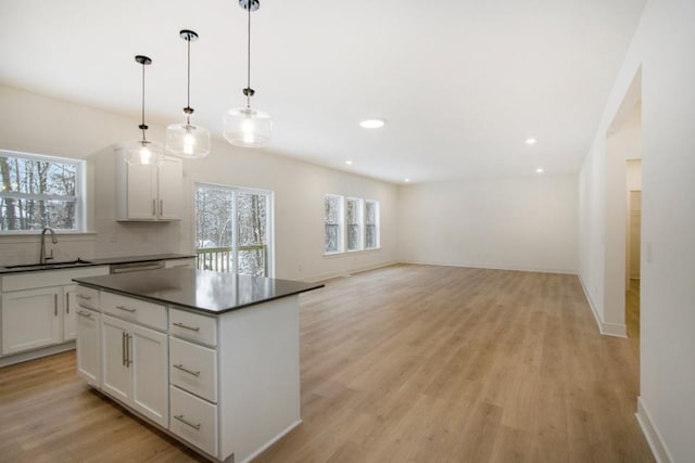 kitchen featuring pendant lighting, backsplash, sink, light hardwood / wood-style flooring, and white cabinetry