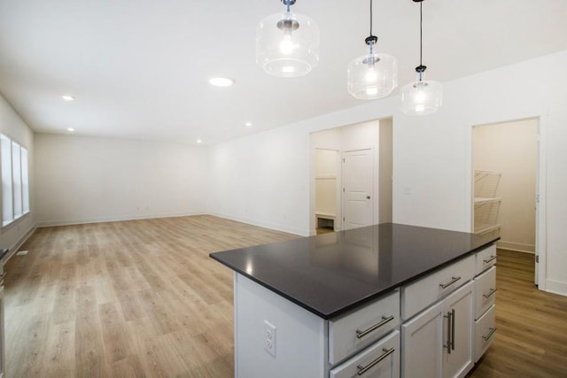 kitchen featuring decorative light fixtures, a kitchen island, and light hardwood / wood-style flooring