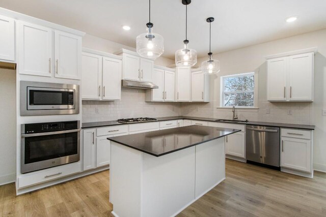 kitchen featuring sink, hanging light fixtures, stainless steel appliances, light hardwood / wood-style floors, and white cabinets