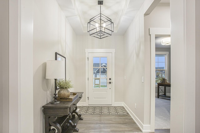 entrance foyer with beamed ceiling, hardwood / wood-style flooring, and a chandelier