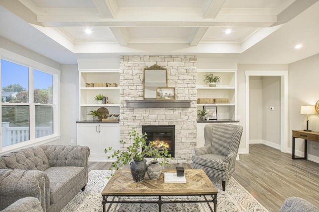 living room featuring light hardwood / wood-style floors, a stone fireplace, and beam ceiling