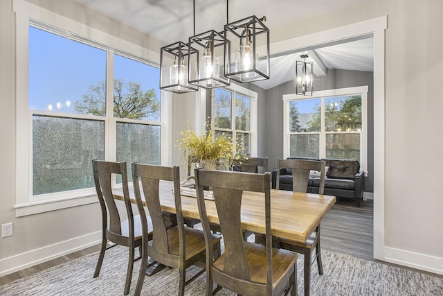 dining area with a chandelier, a wealth of natural light, lofted ceiling with beams, and wood-type flooring