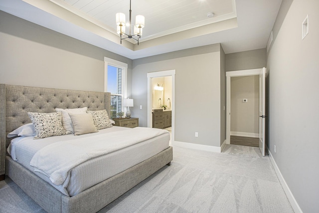 bedroom featuring light carpet, connected bathroom, a tray ceiling, and a notable chandelier