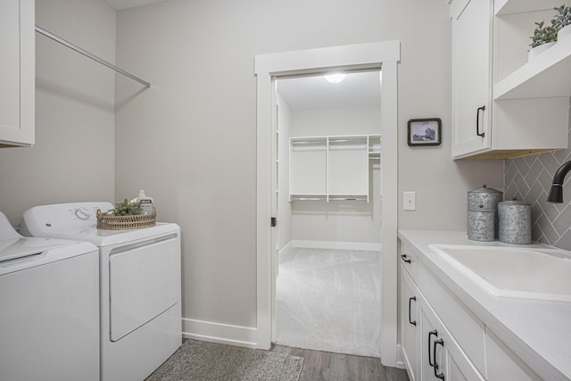 laundry area with light hardwood / wood-style floors, cabinets, sink, and washing machine and clothes dryer