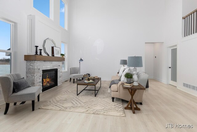 living room with light wood-type flooring, plenty of natural light, a fireplace, and visible vents