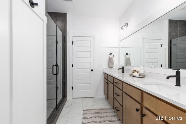 bathroom with marble finish floor, a sink, a shower stall, and double vanity