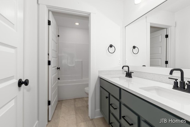 bathroom with double vanity, tub / shower combination, a sink, and toilet