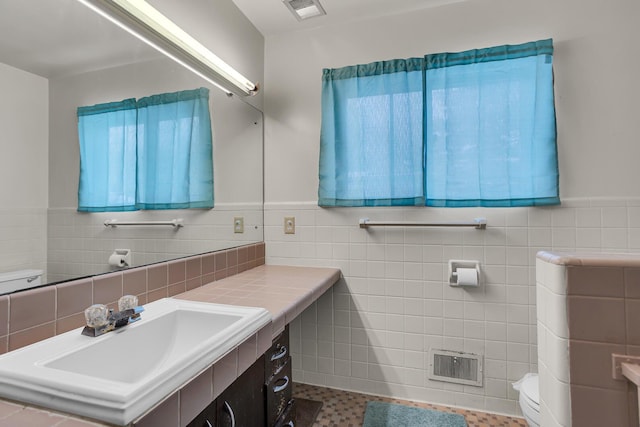 bathroom featuring toilet, tile walls, and sink