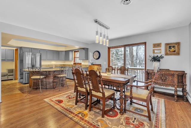 dining area with a baseboard heating unit, a chandelier, and light hardwood / wood-style floors