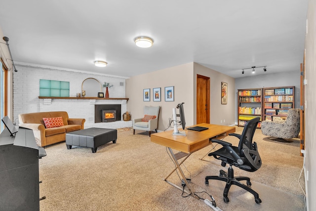 home office with brick wall, a brick fireplace, carpet flooring, and rail lighting