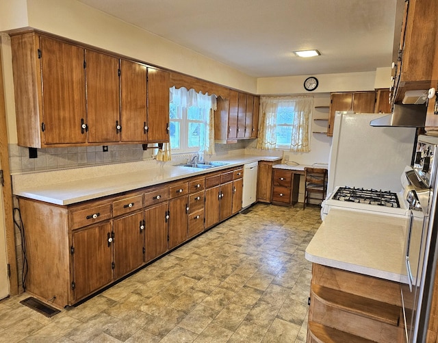 kitchen with decorative backsplash, white appliances, and sink