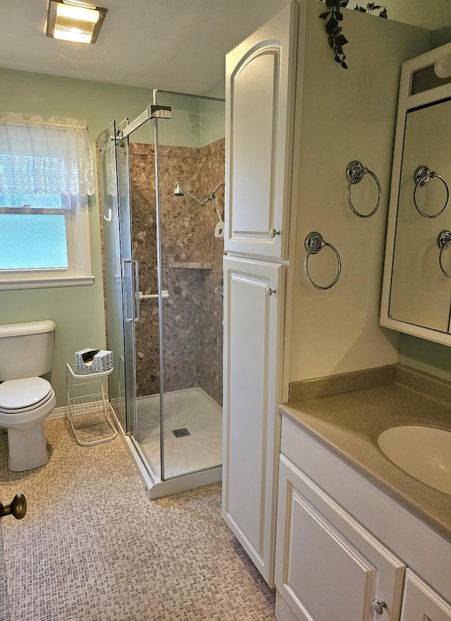 bathroom with tile patterned floors, a shower with door, vanity, and toilet