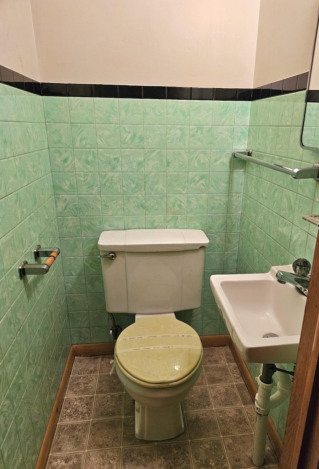 bathroom with tile patterned floors, toilet, tile walls, and sink