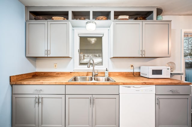 kitchen featuring white appliances, plenty of natural light, butcher block counters, and sink