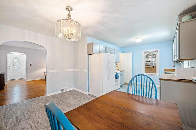 dining room featuring sink, an inviting chandelier, and light wood-type flooring