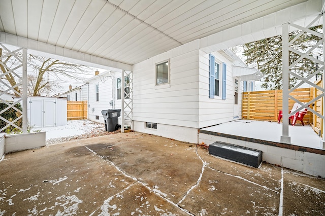 snow covered patio featuring a shed