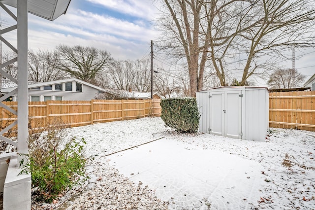 snowy yard featuring a patio area and a storage unit