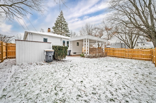 snow covered back of property featuring a storage shed