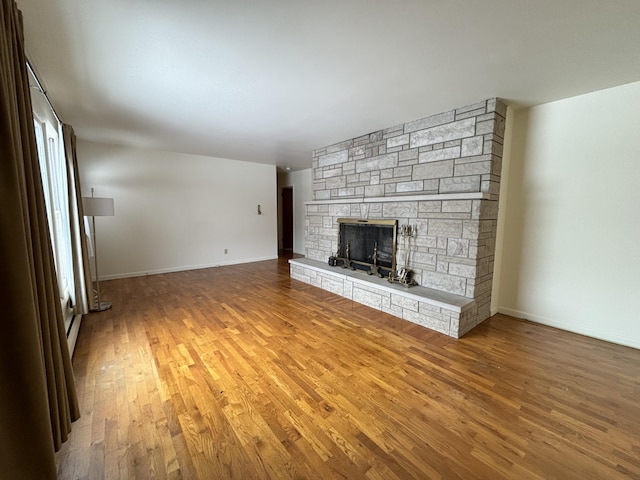 unfurnished living room with a stone fireplace and hardwood / wood-style flooring