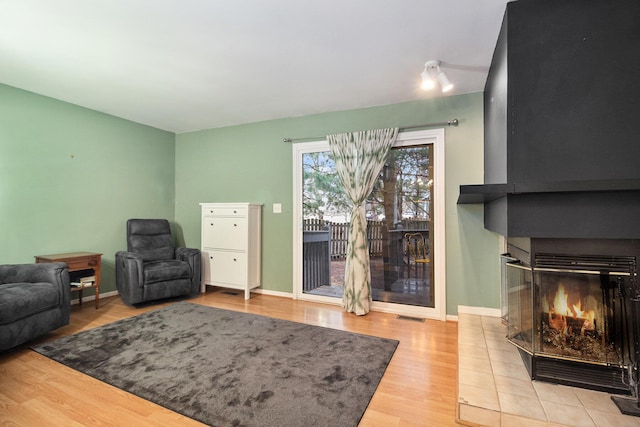 living room featuring light hardwood / wood-style floors and a tiled fireplace