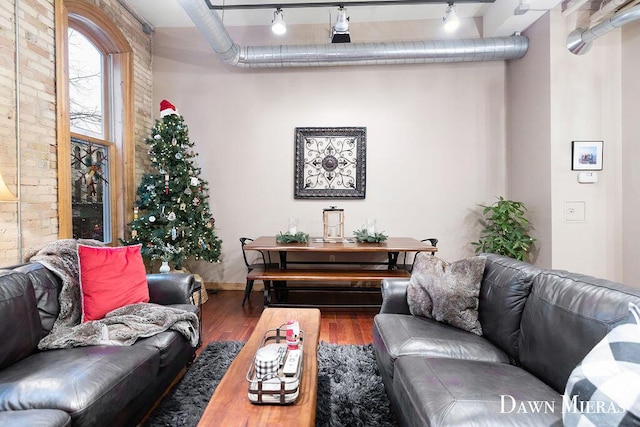 living room with track lighting, brick wall, and dark hardwood / wood-style floors