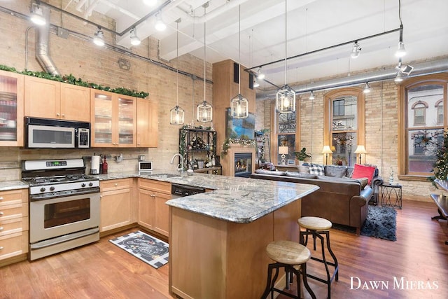 kitchen with sink, a high ceiling, gas range oven, decorative light fixtures, and a breakfast bar area