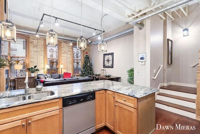 kitchen featuring light stone countertops, sink, dark hardwood / wood-style flooring, stainless steel dishwasher, and brick wall