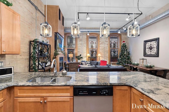 kitchen with sink, brick wall, stainless steel dishwasher, and track lighting