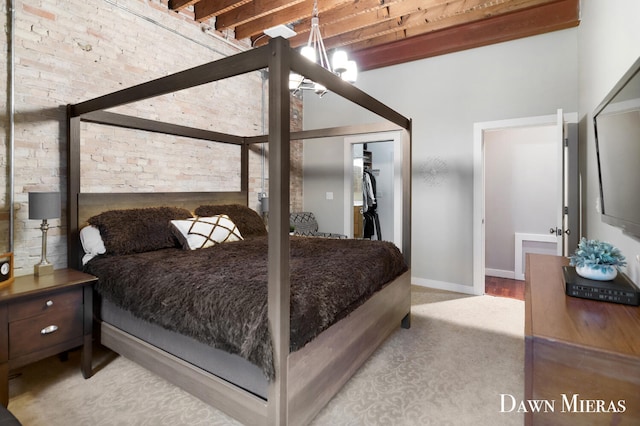 carpeted bedroom with beam ceiling, a closet, and brick wall