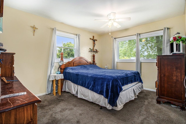 bedroom with multiple windows, ceiling fan, and dark carpet