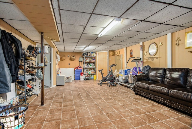 basement with tile patterned flooring, a paneled ceiling, and wooden walls