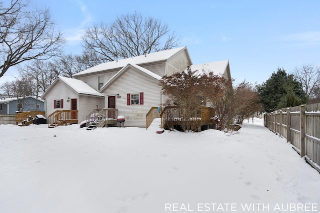 snow covered rear of property with a deck