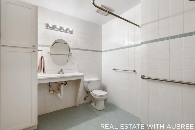 bathroom featuring toilet, tile patterned flooring, and tile walls