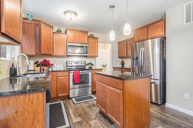 kitchen featuring pendant lighting, sink, dark hardwood / wood-style floors, appliances with stainless steel finishes, and a kitchen island