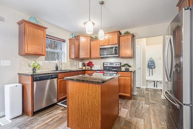 kitchen with hardwood / wood-style floors, a center island, hanging light fixtures, sink, and appliances with stainless steel finishes