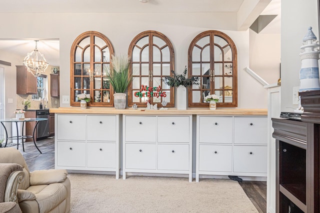 kitchen featuring sink, stainless steel dishwasher, butcher block countertops, hardwood / wood-style floors, and a chandelier