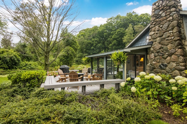 wooden deck with a sunroom and an outdoor fire pit