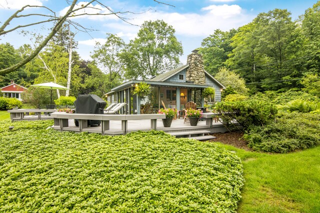 rear view of property featuring a sunroom and a wooden deck