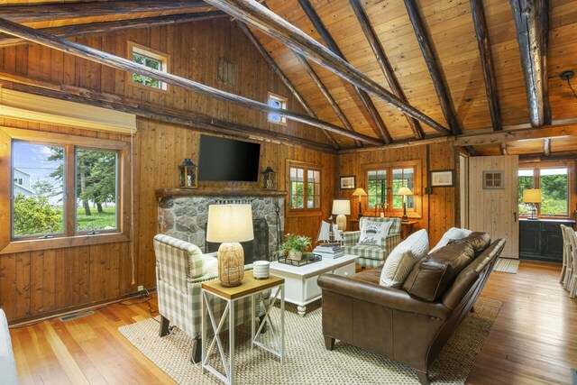 living room featuring beamed ceiling, light wood-type flooring, wooden walls, and wooden ceiling