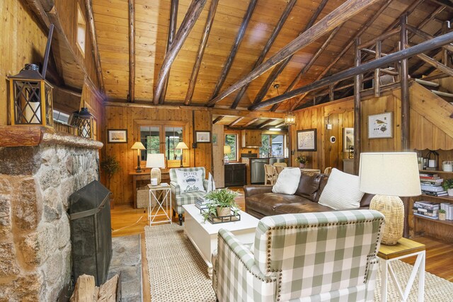 living room featuring lofted ceiling with beams, light hardwood / wood-style floors, wooden walls, and wood ceiling