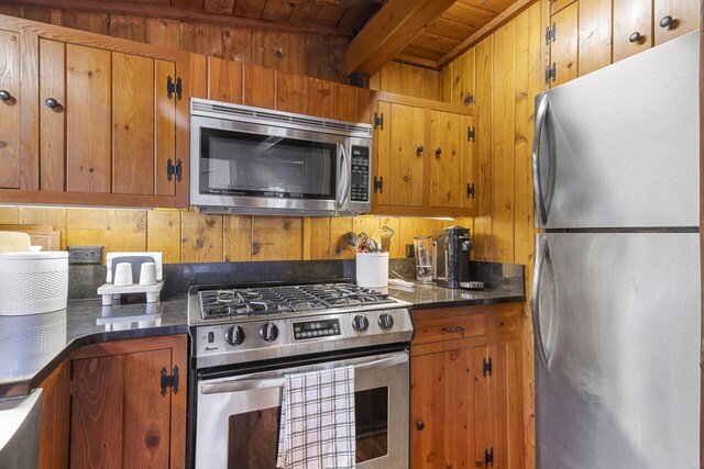 kitchen featuring appliances with stainless steel finishes, beam ceiling, wooden walls, and wood ceiling