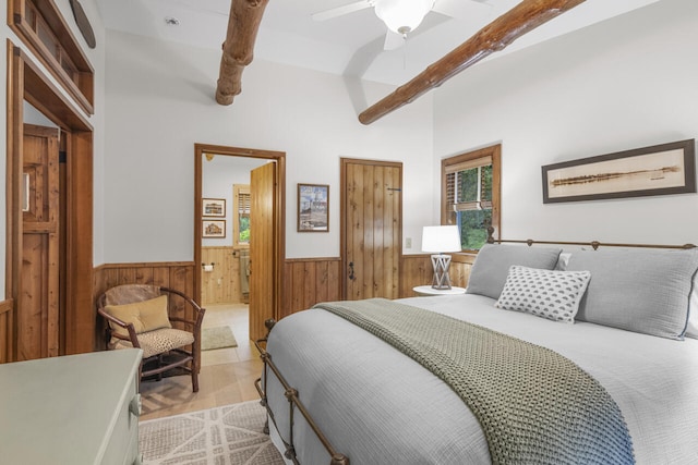 bedroom featuring ensuite bathroom, lofted ceiling with beams, wooden walls, ceiling fan, and light wood-type flooring