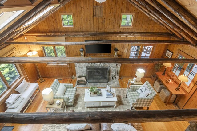 living room featuring plenty of natural light, wood walls, and high vaulted ceiling